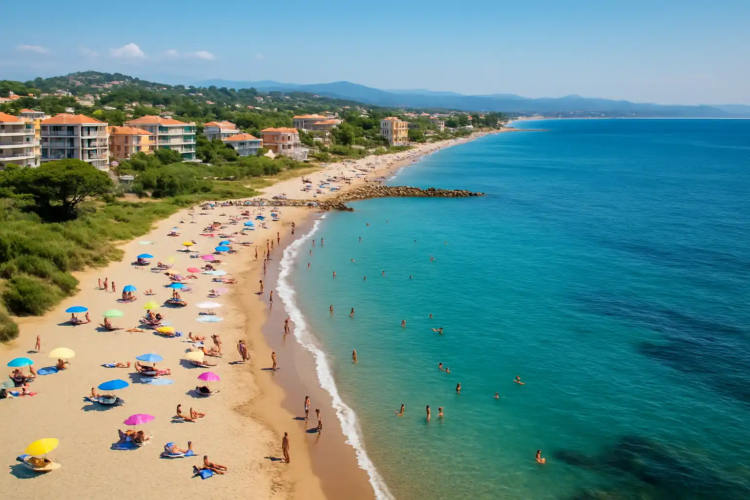 Saint-Aygulf plage : quelles sont les plus belles plages du quartier ? 2 Aperçu aérien d’une plage de Saint-Aygulf avec sable fin, eaux turquoise et vacanciers, face aux collines et habitations de la Côte d’Azur.